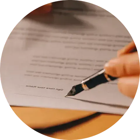 Primer plano de una mano que utiliza una pluma estilográfica para firmar un documento.
