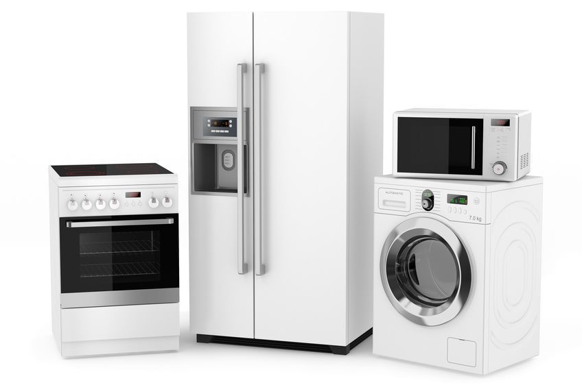 Un refrigerador, una lavadora, un microondas y un horno están sentados uno al lado del otro sobre un fondo blanco.