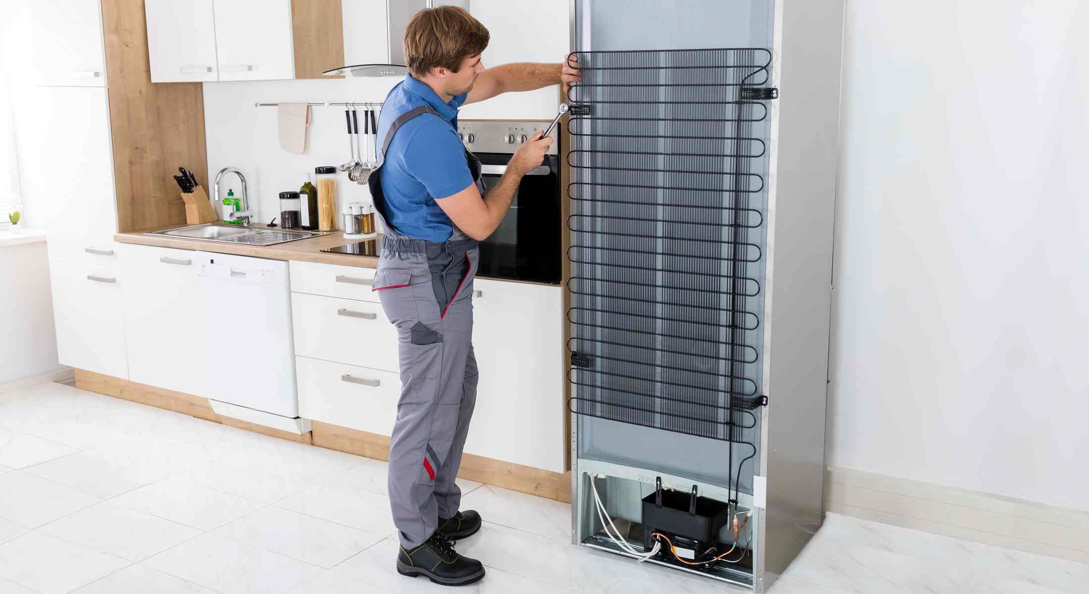 Un hombre está arreglando un refrigerador en una cocina.