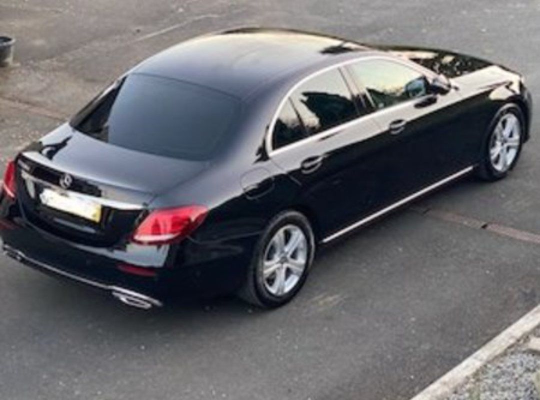 Un Mercedes Benz negro está estacionado en un estacionamiento.
