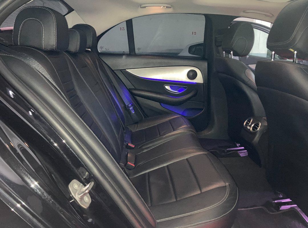 El asiento trasero de un coche negro con luces violetas en la puerta.