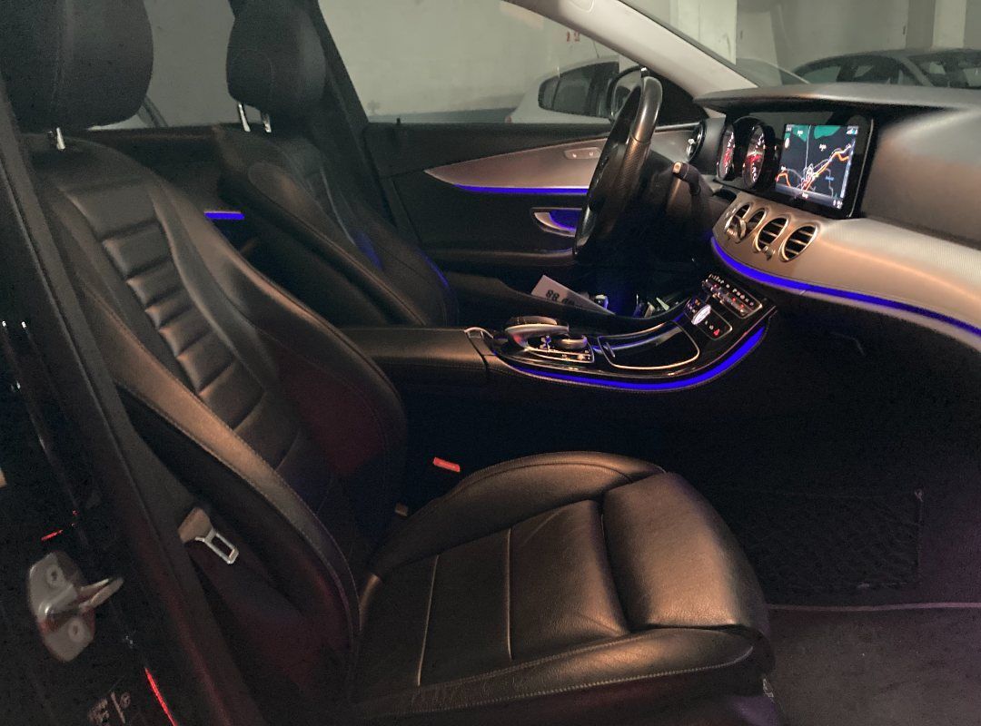 El interior de un coche negro con luces azules en el tablero.