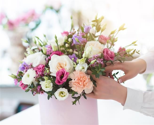 Composition de fleurs dans un cache pot rose.