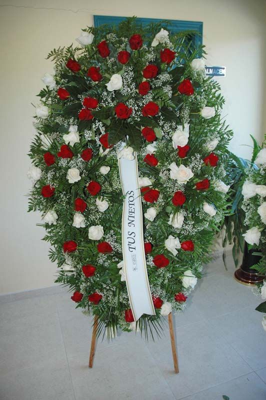 Una corona de flores rojas y blancas con una cinta que dice