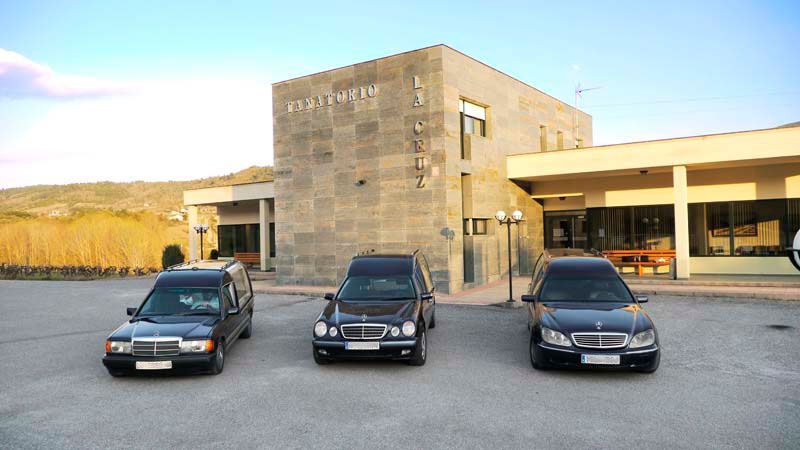 Tres coches negros están aparcados delante de un edificio.