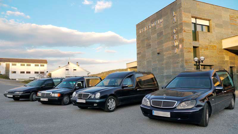 Una fila de coches negros están aparcados delante de un edificio.