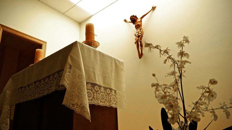 Una estatua de Jesús cuelga del techo sobre una mesa.