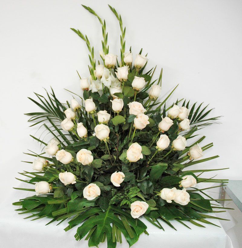 Un ramo de rosas blancas y vegetación sobre una mesa.