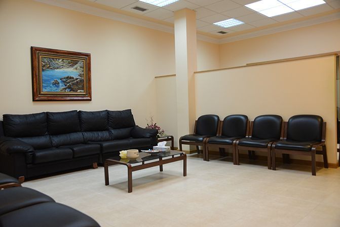 Una sala de estar con un sofá, sillas, una mesa de café y un cuadro en la pared.