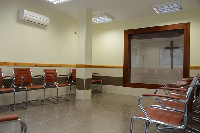 Una sala de espera con sillas y una cruz en la pared.