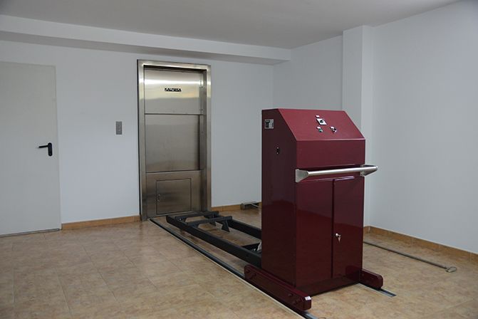 Una habitación con un ascensor de acero inoxidable y una máquina roja.