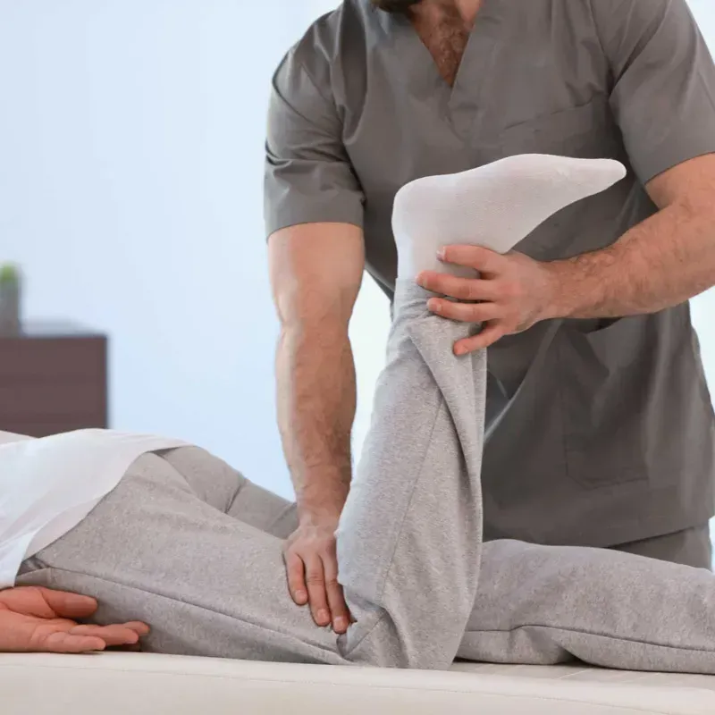 Un hombre está estirando la pierna de una mujer en una cama.
