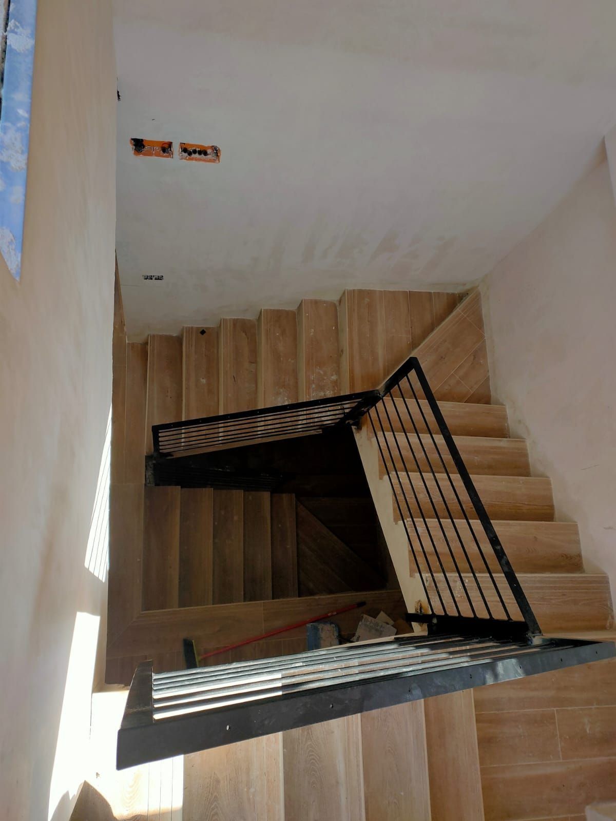 Una escalera de madera con barandilla de metal en una casa.
