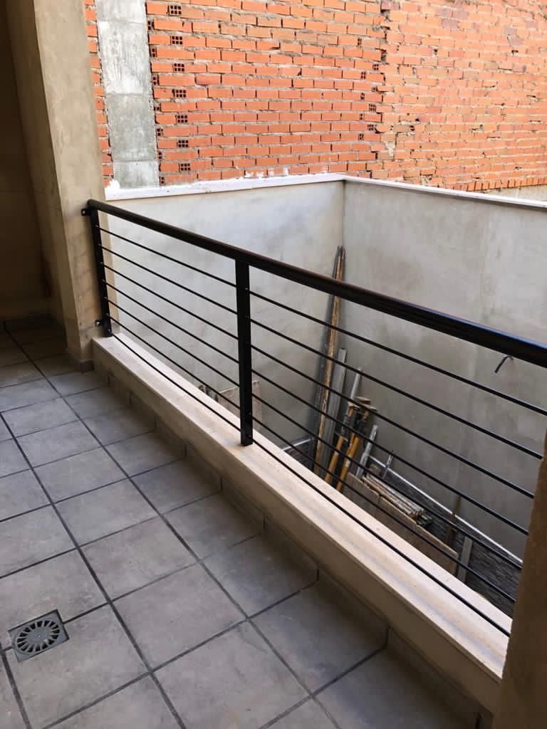 Un balcón con una barandilla negra y una escalera encima.