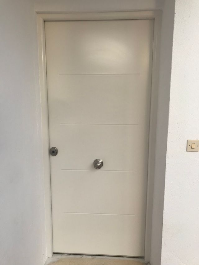Una puerta blanca está en un pasillo al lado de una pared.