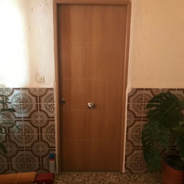 Una puerta de madera en una habitación con azulejos en la pared.