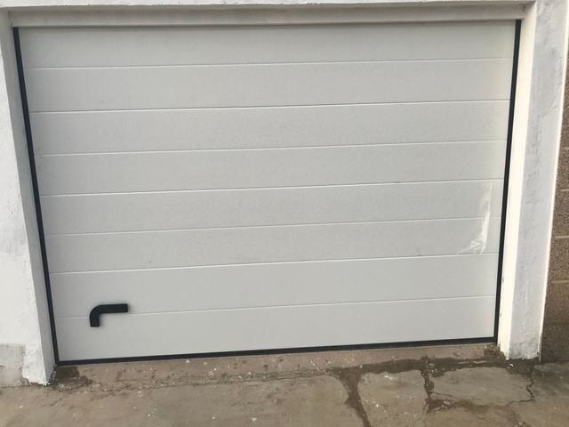 Una puerta de garaje blanca está situada al costado de un edificio.