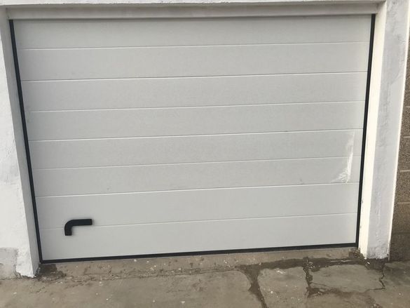 Una puerta de garaje blanca con una manija negra está abierta.
