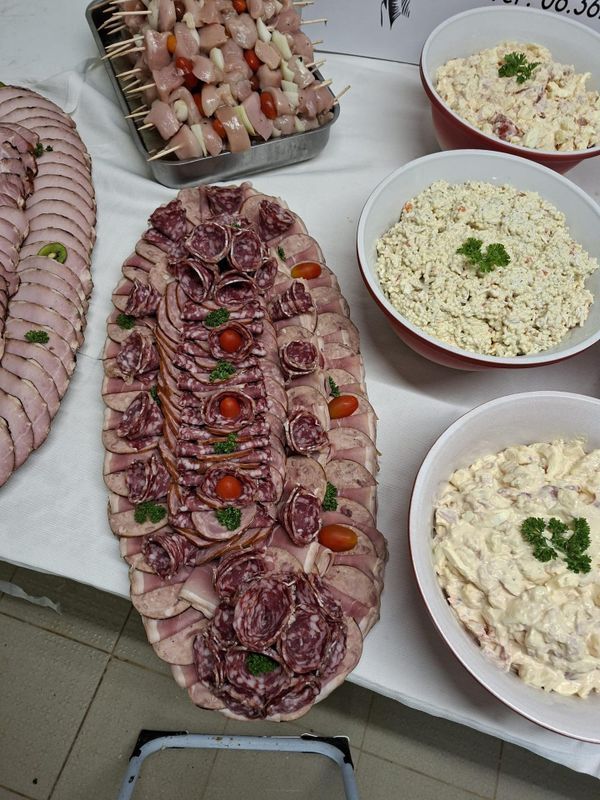 Buffet : charcuterie tranchée, brochettes et bols de salades crémeuses.