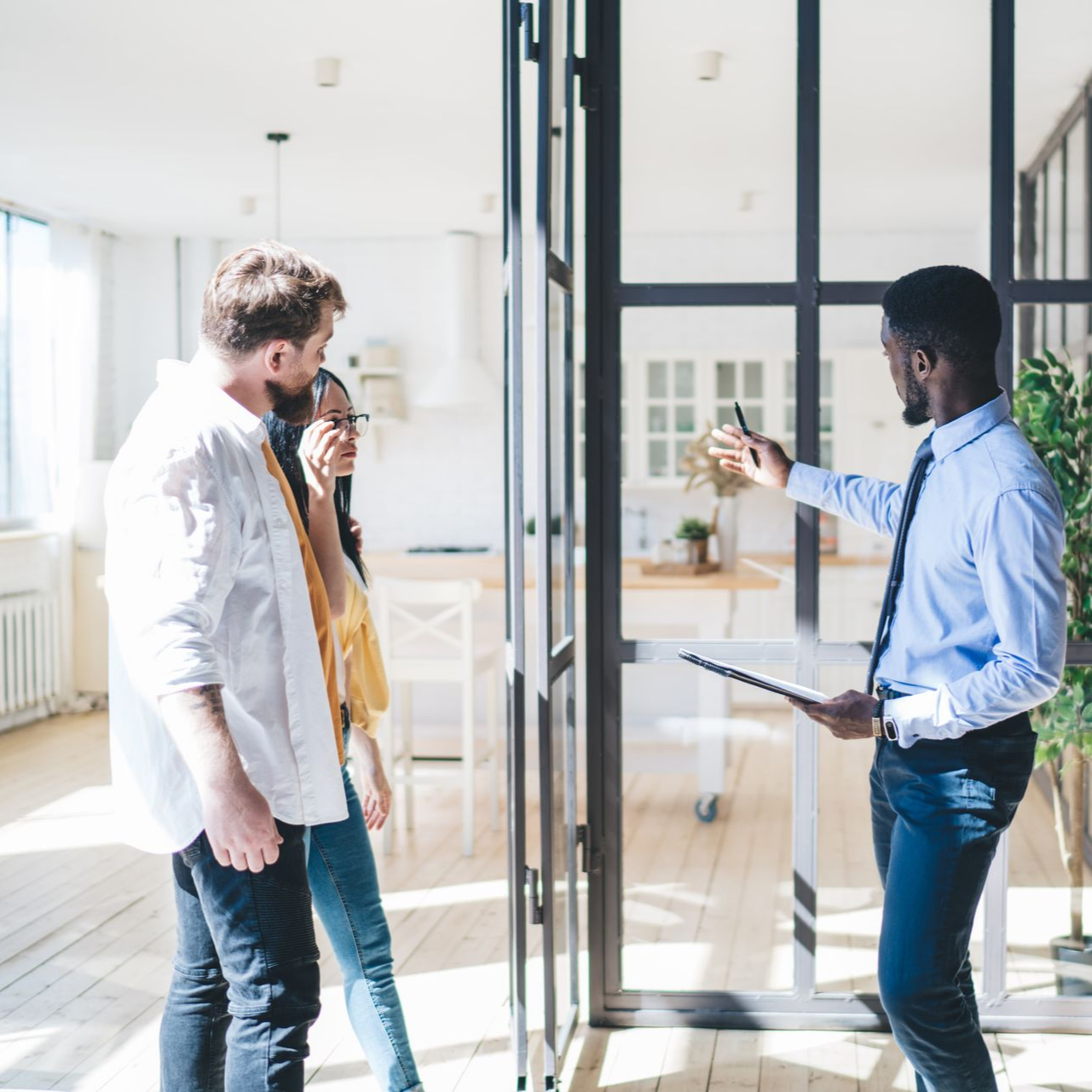 Un agent immobilier fait visiter une maison aux murs de verre à un couple.