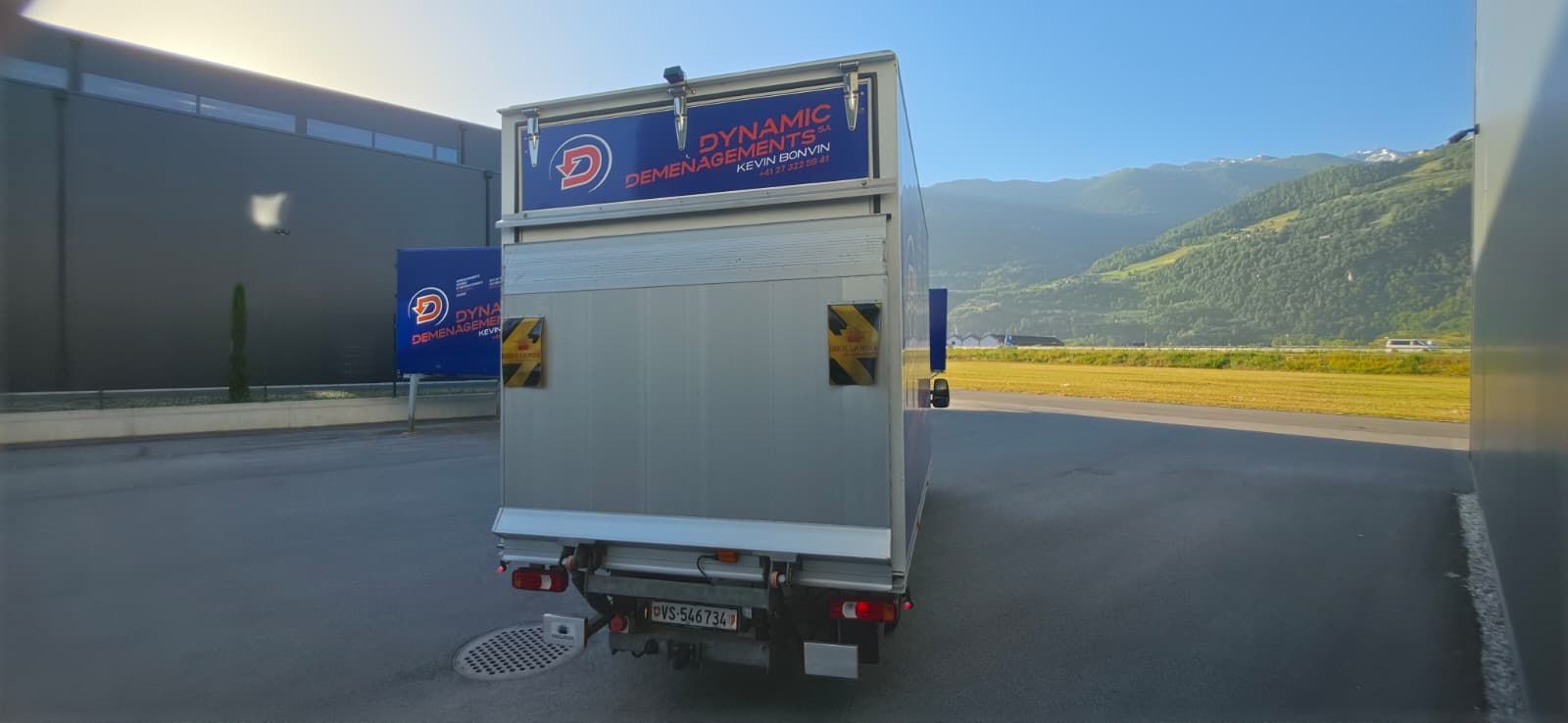 Un semi-remorque bleu avec une remorque fourgon est stationné dans un garage d'entrepôt.