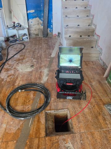 Cámara de inspección en piso de madera cerca de un agujero en el piso y la escalera en una habitación dañada.