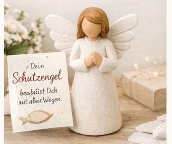 Engelsfigur mit gefalteten Händen, daneben eine Karte mit der Aufschrift „Dein Schutzengel begleitet dich auf allen Wegen“.