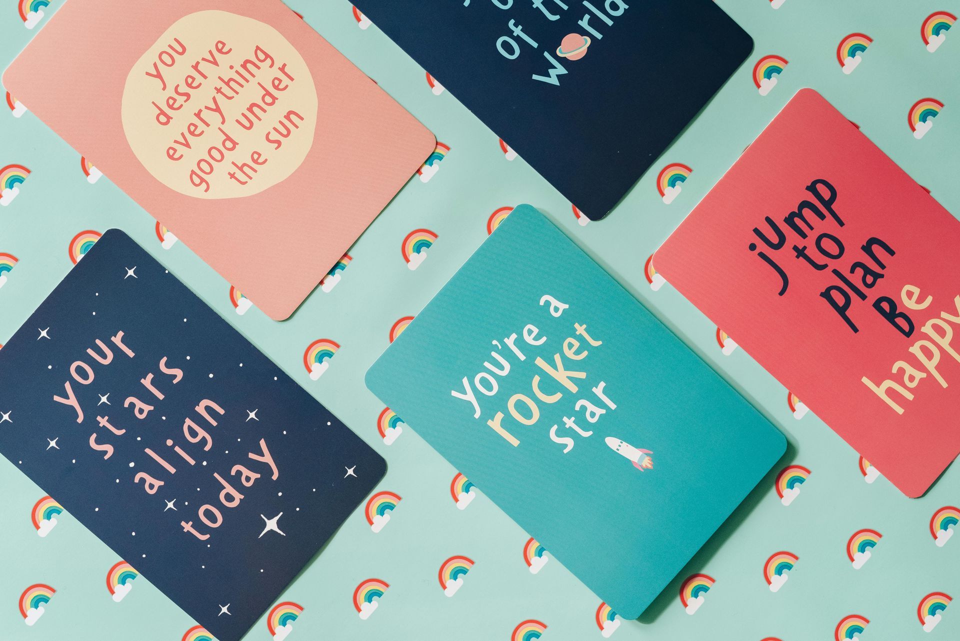 Five colorful notebooks with positive affirmations on a rainbow patterned background.