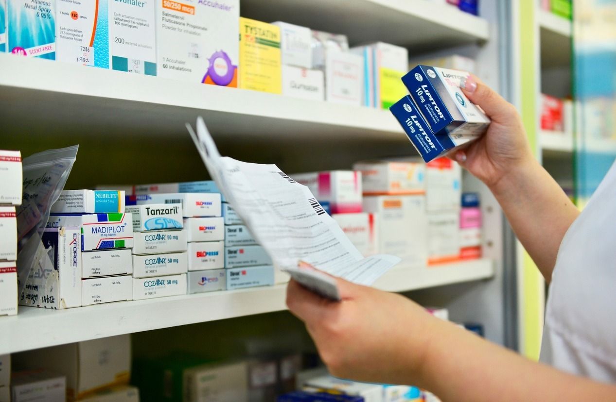 Un farmacéutico está mirando una caja de pastillas en una farmacia.
