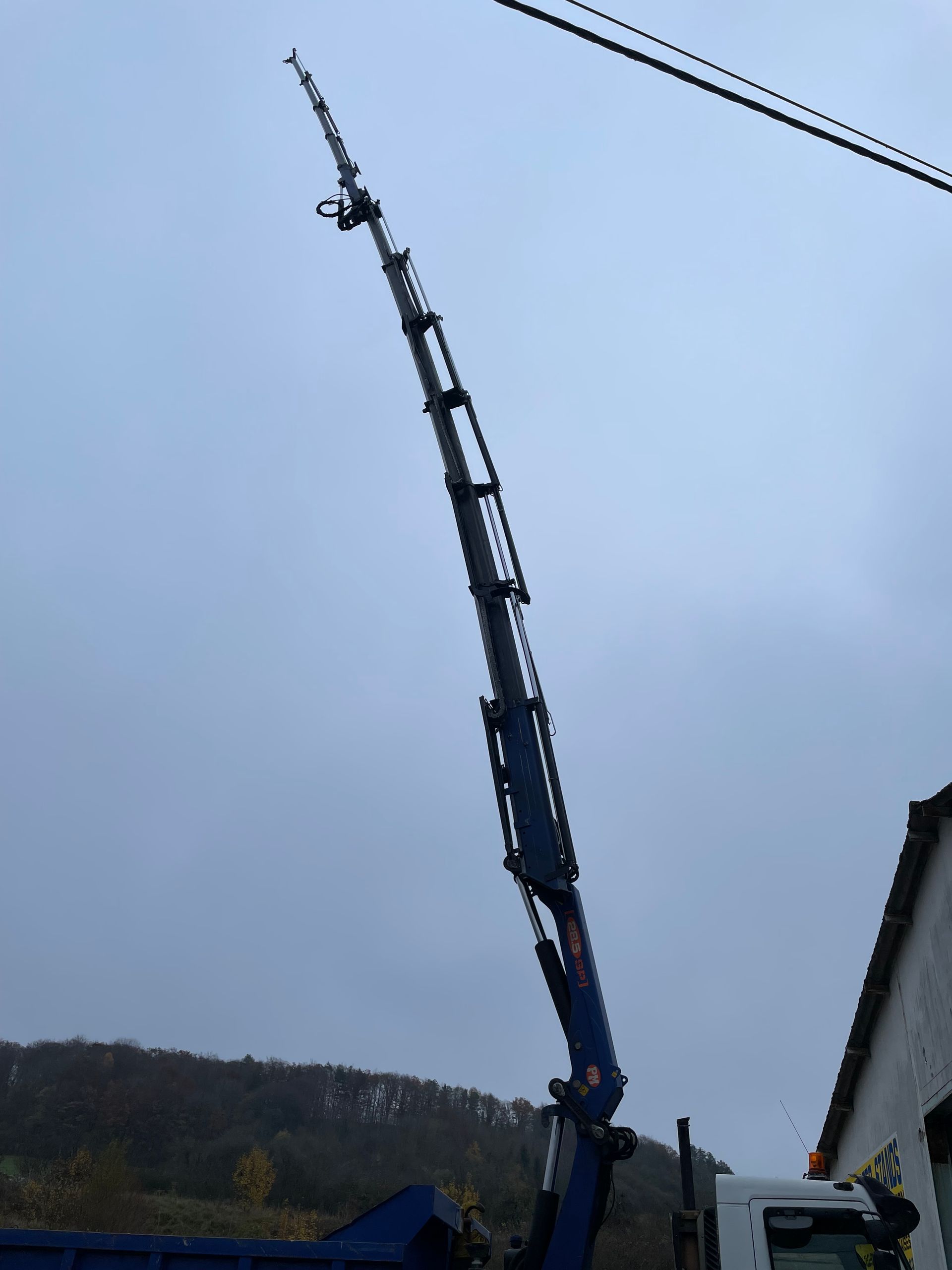 Une personne se tient sur un toit de tuiles, à côté de rangées de panneaux solaires.