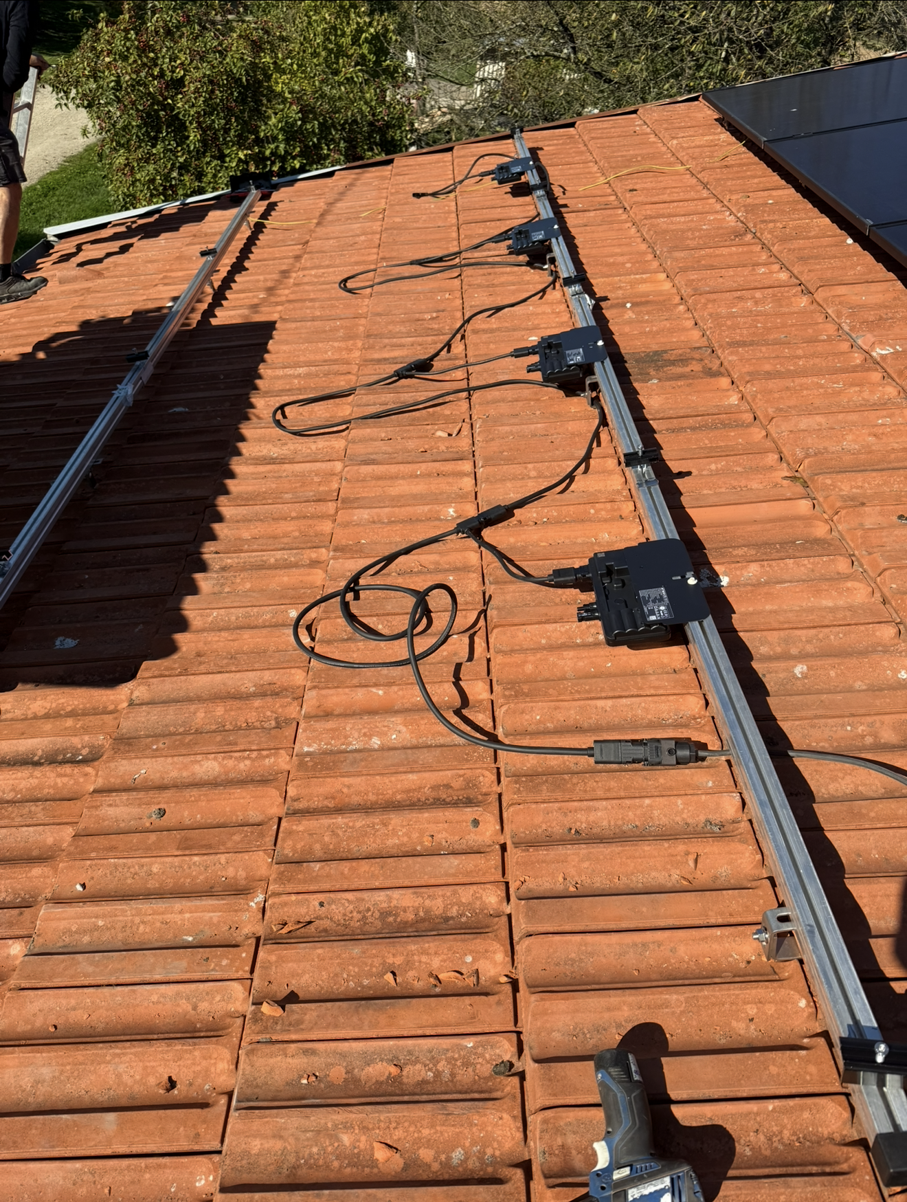 Rails de fixation pour panneaux solaires et micro-onduleurs avec câblage électrique, installés sur un toit.