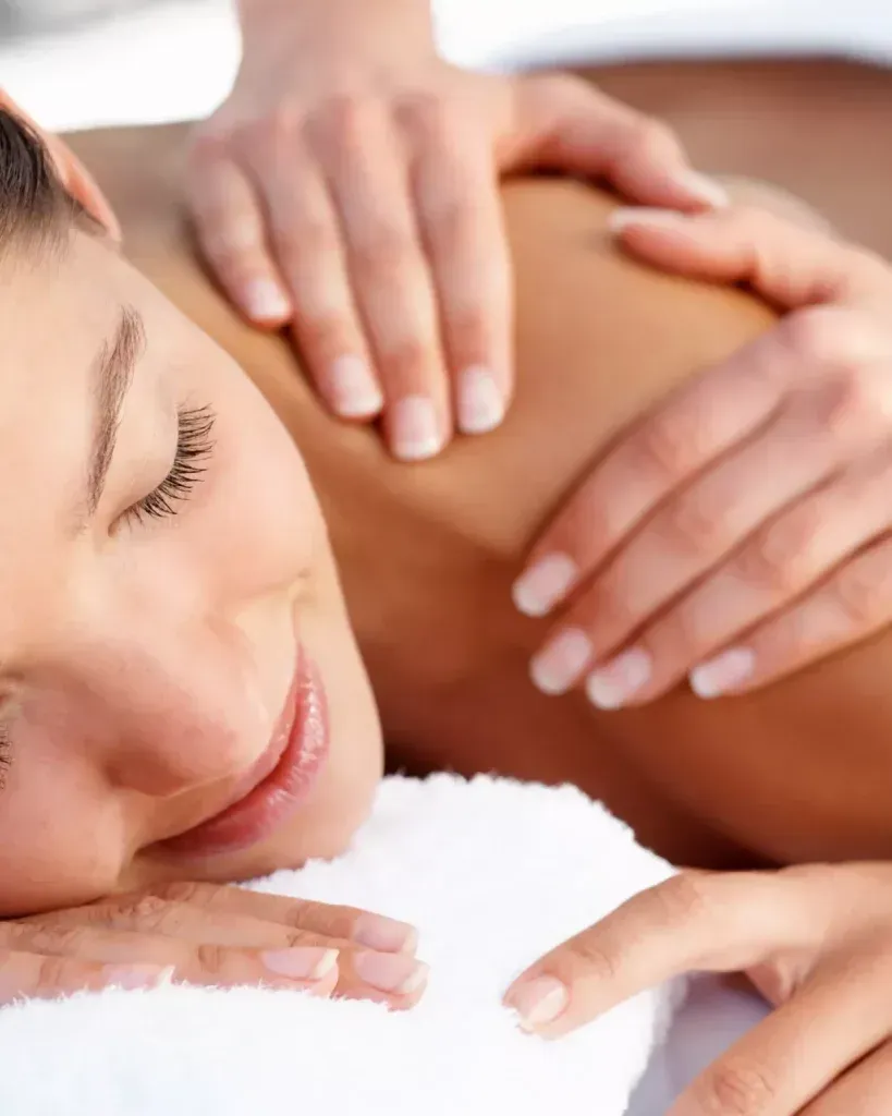 Mujer con diadema y bata blancas, acostada con los ojos cerrados, probablemente sometiéndose a un tratamiento facial.