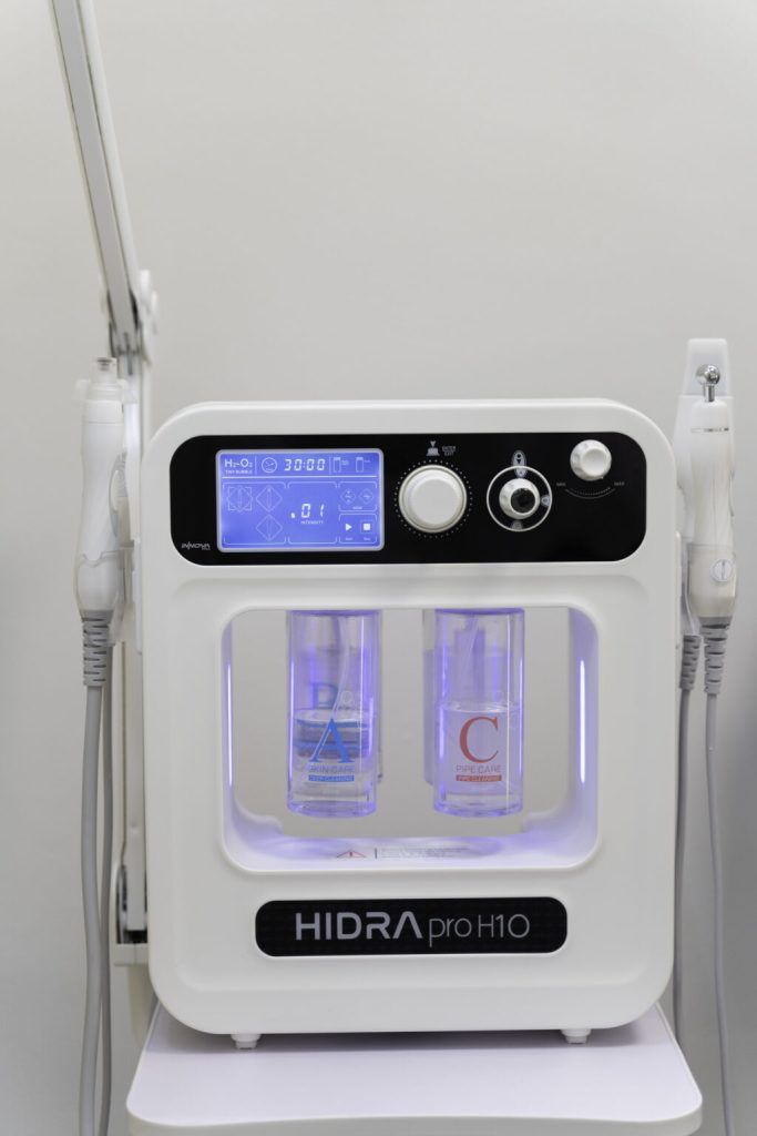 Mujer con diadema y bata blancas, acostada con los ojos cerrados, probablemente sometiéndose a un tratamiento facial.