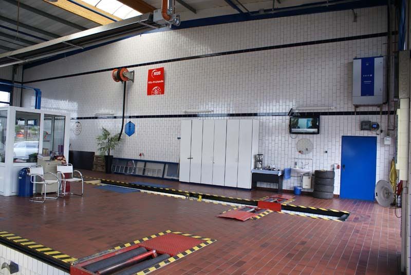 Eine leere Garage mit rotem Boden und blauer Tür