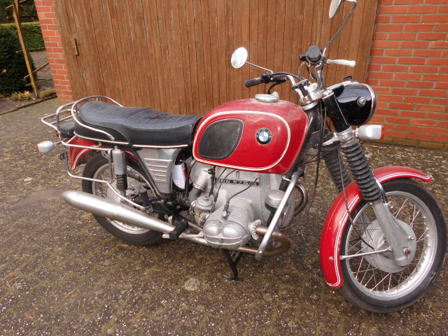 Ein rotes Motorrad steht vor einem hölzernen Garagentor