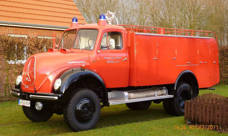 Ein altes rotes Feuerwehrauto steht auf einer Wiese.