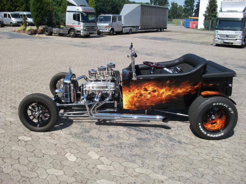 Ein Hot Rod mit aufgemalten Flammen steht auf einem Parkplatz