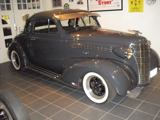 Ein schwarzes Auto steht in einer Garage mit einem Schild darüber, auf dem steht: Story