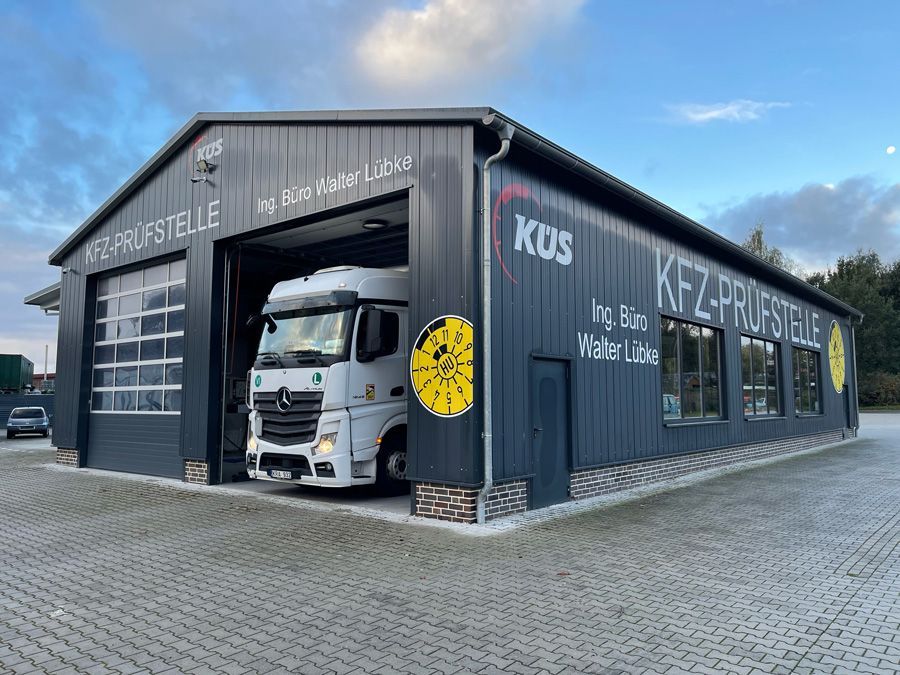 Vor einem großen Gebäude parkt ein LKW.