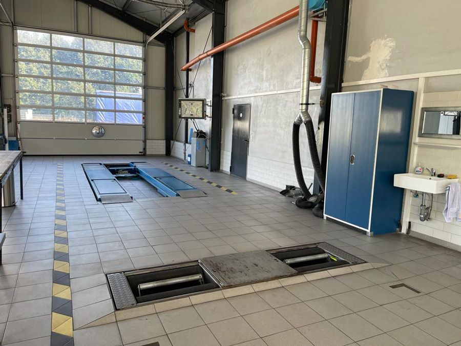 Eine große leere Garage mit einem Waschbecken und einem blauen Schrank.