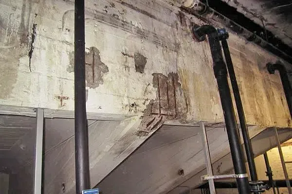 Renzel-Mangold Bautenschutz e.K. - Betonwand mit Schäden und freiliegenden Stahlstreben an Unterseite eines Pools