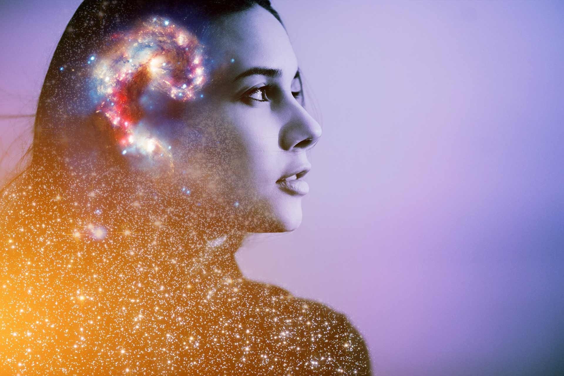 Una doble exposición del rostro de una mujer con una galaxia en su cabeza.