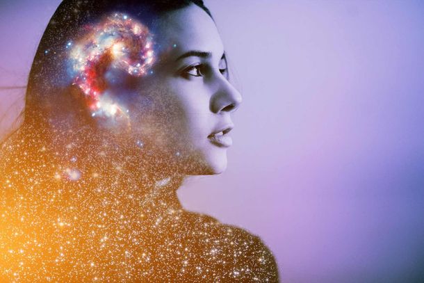 Una doble exposición del rostro de una mujer con una galaxia en su cabeza.