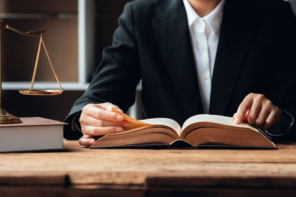 Una mujer está sentada en una mesa leyendo un libro.