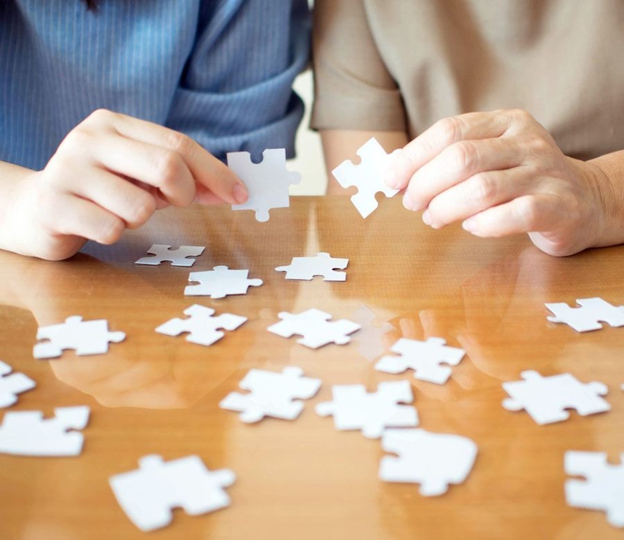 Dos personas están jugando con piezas de rompecabezas sobre una mesa.