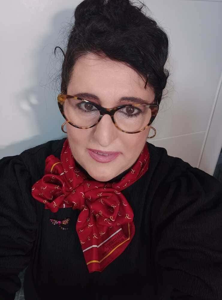 Una mujer que lleva gafas y un pañuelo rojo se está tomando un selfie.