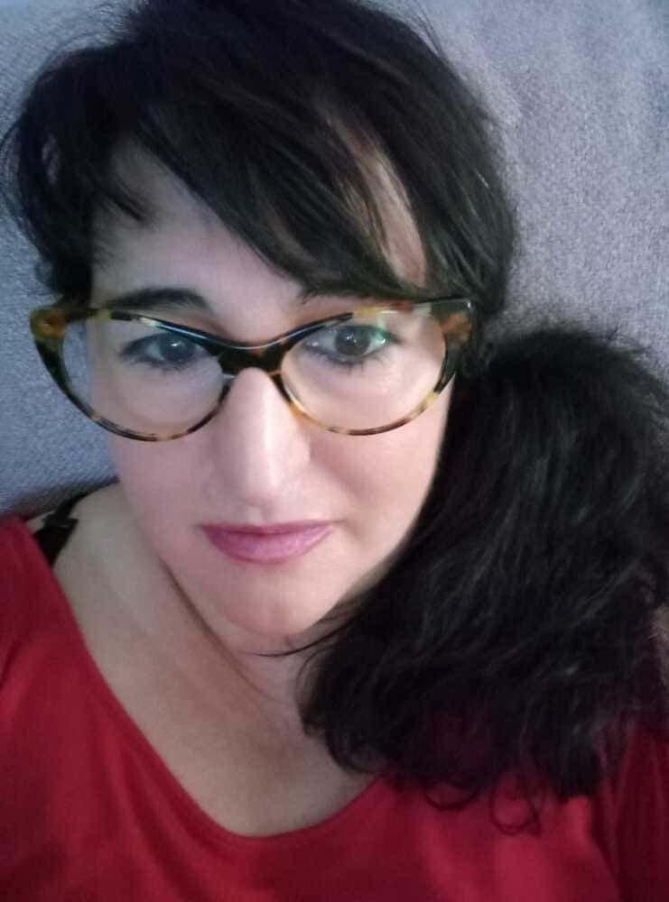 Una mujer que lleva gafas y una camiseta roja se está tomando un selfie.