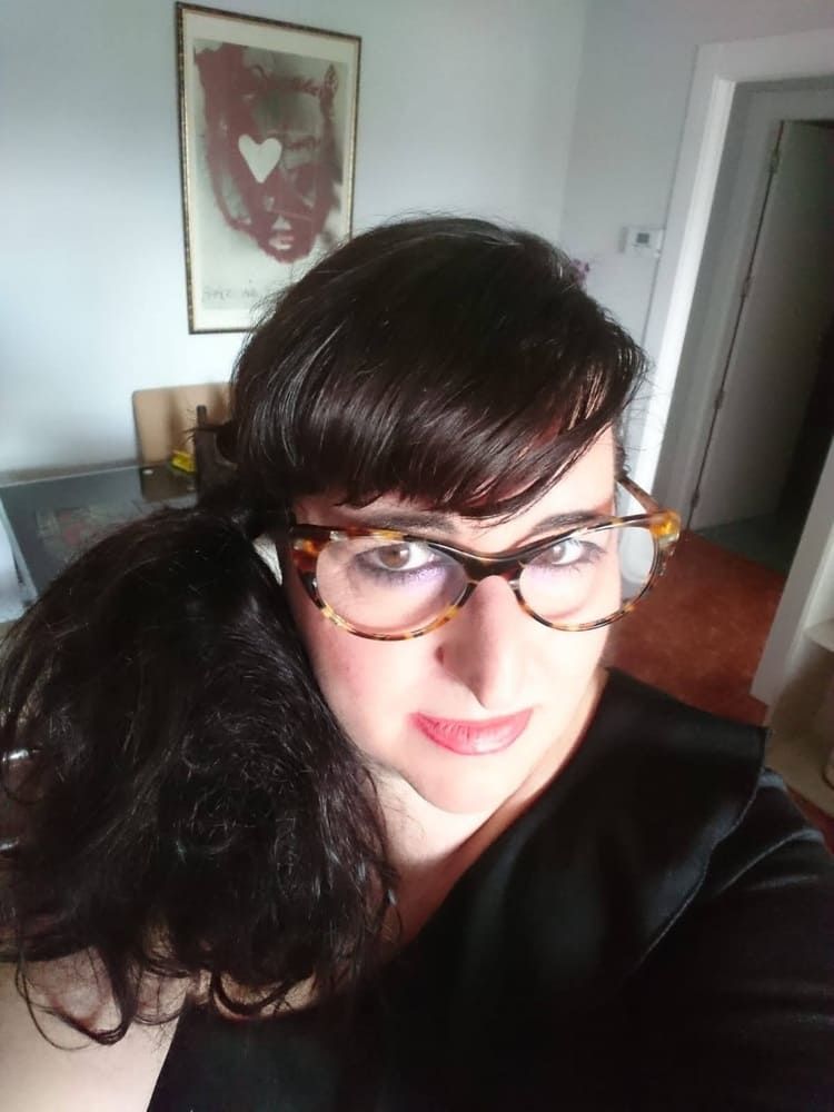 Una mujer que lleva gafas y una cola de caballo se está tomando un selfie en una habitación.