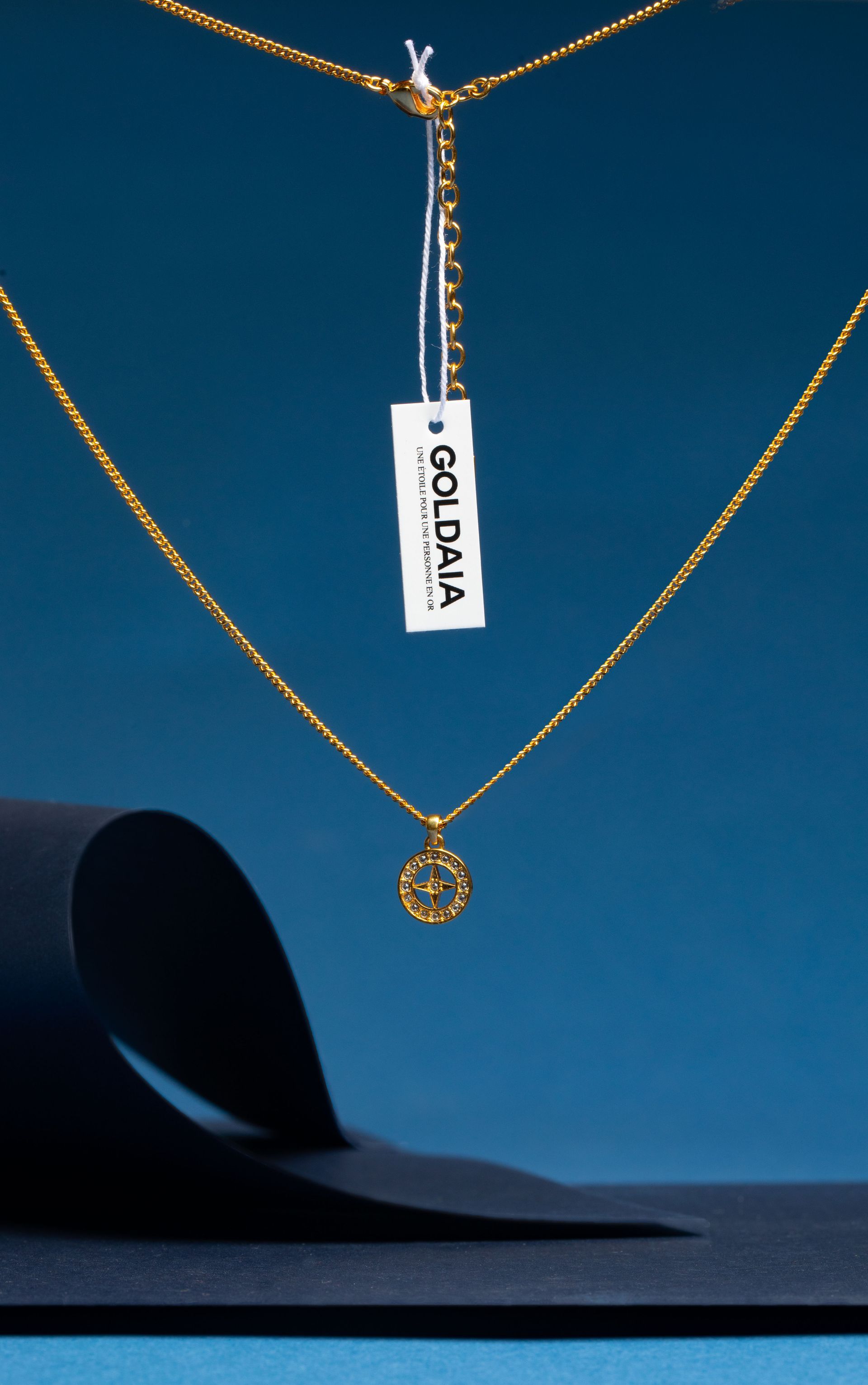 Collier en or avec pendentif et étiquette sur fond bleu