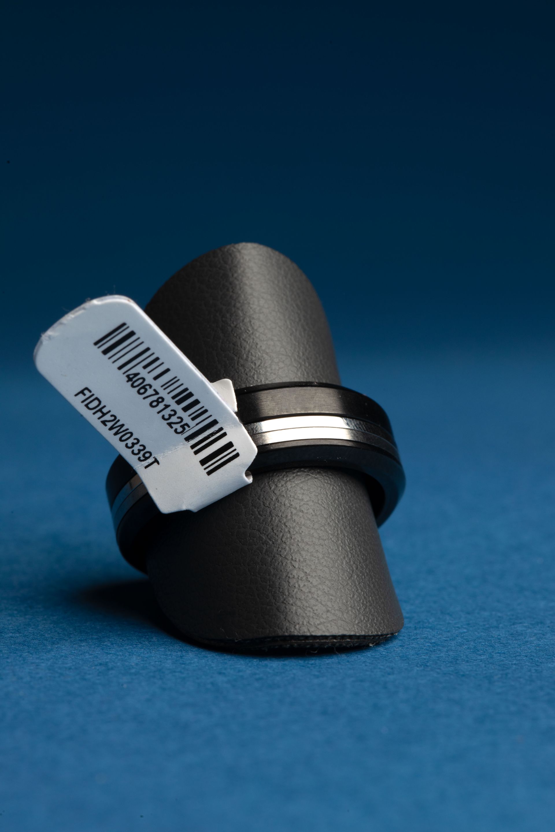 Bague noire et argenté sur un présentoir avec une étiquette de code-barres